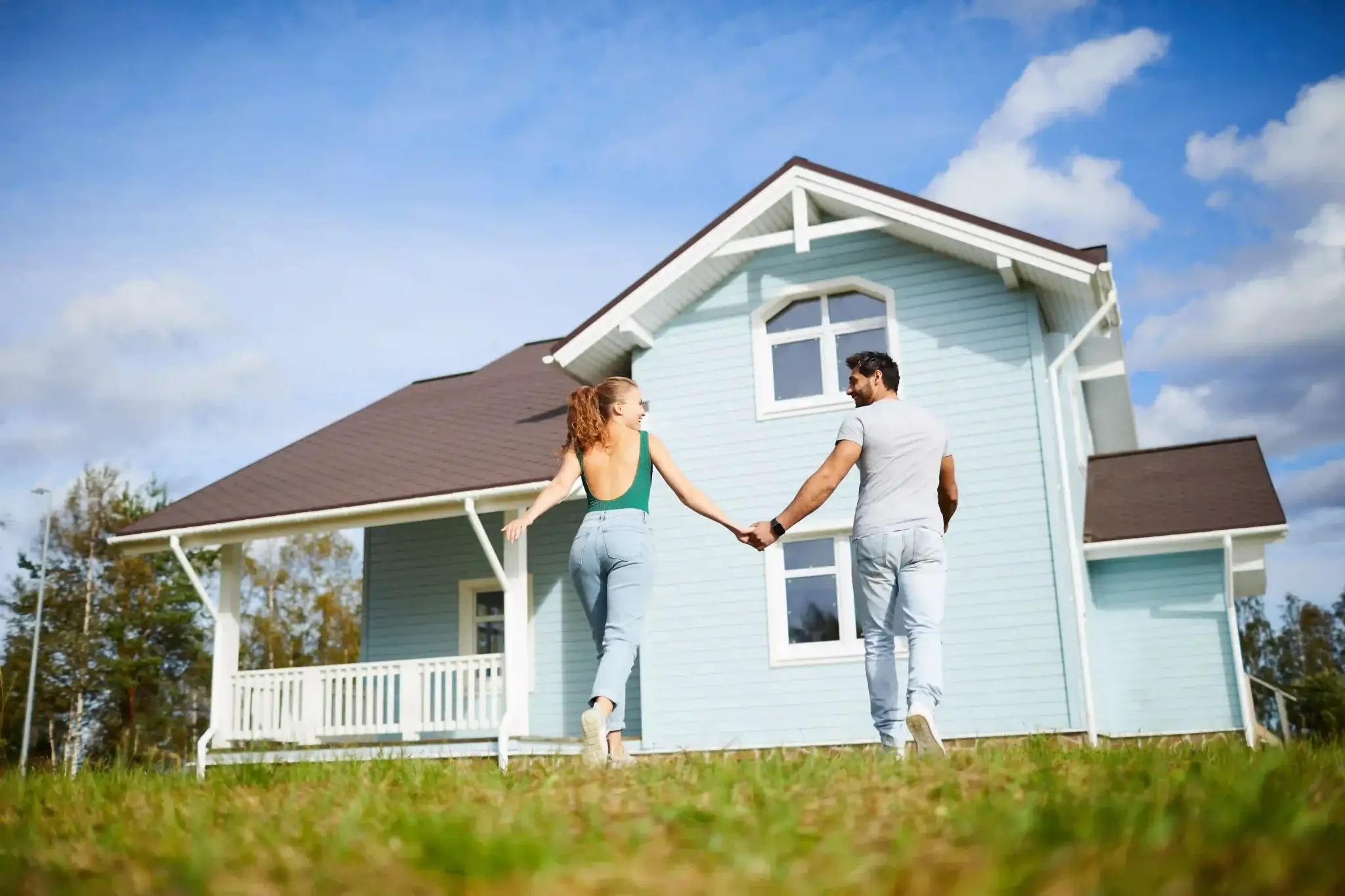 Começar o ano com uma casa nova: casal de mãos dadas em frente a uma casa