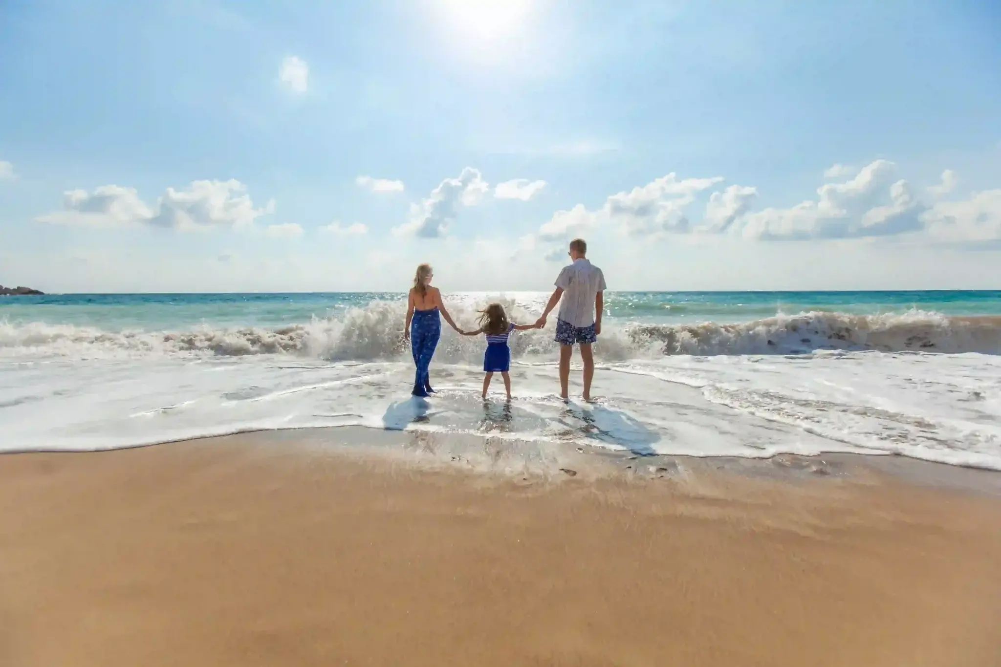 Praia da Pinheira, em Santa Catarina: família composta de pai, mãe e criança com os pés na água da praia