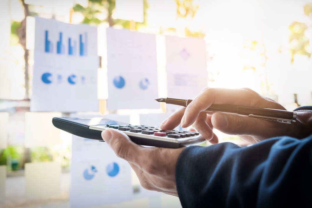 Auditoria fiscal em condomínio: homem usando calculadora enquanto olha para gráficos colados em um vidro