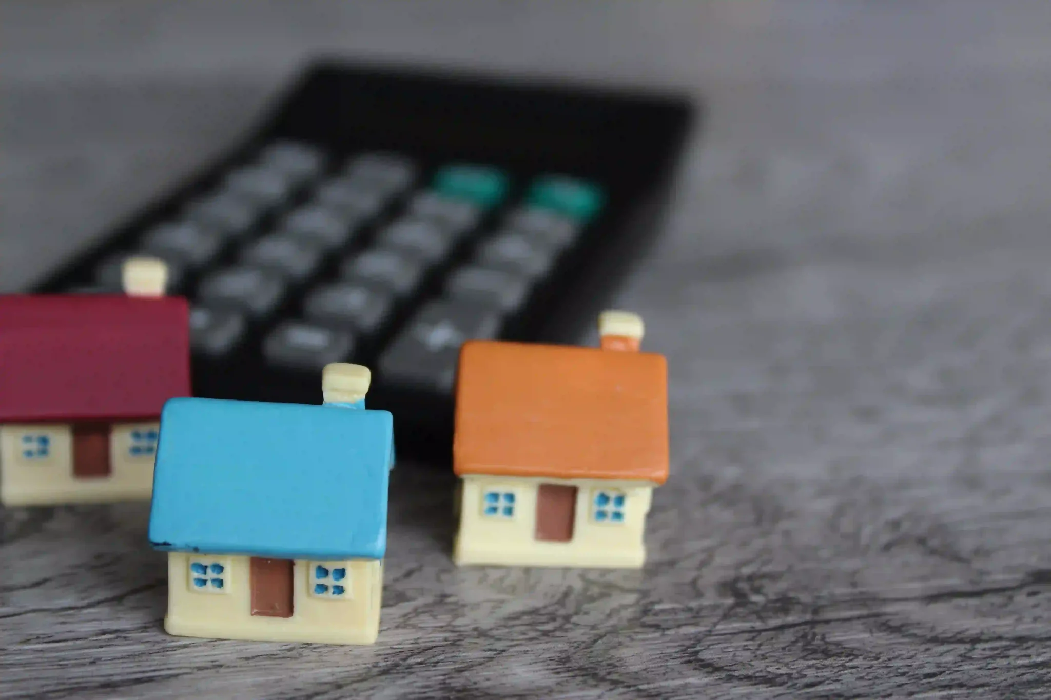 Comprar imóvel para investir: miniaturas de casas próximas a calculadora