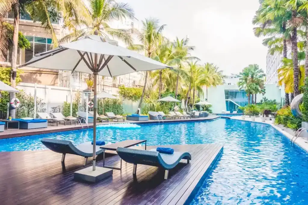 Condomínio resort: imagem de piscina com deck, guarda-sol, palmeiras e cadeiras