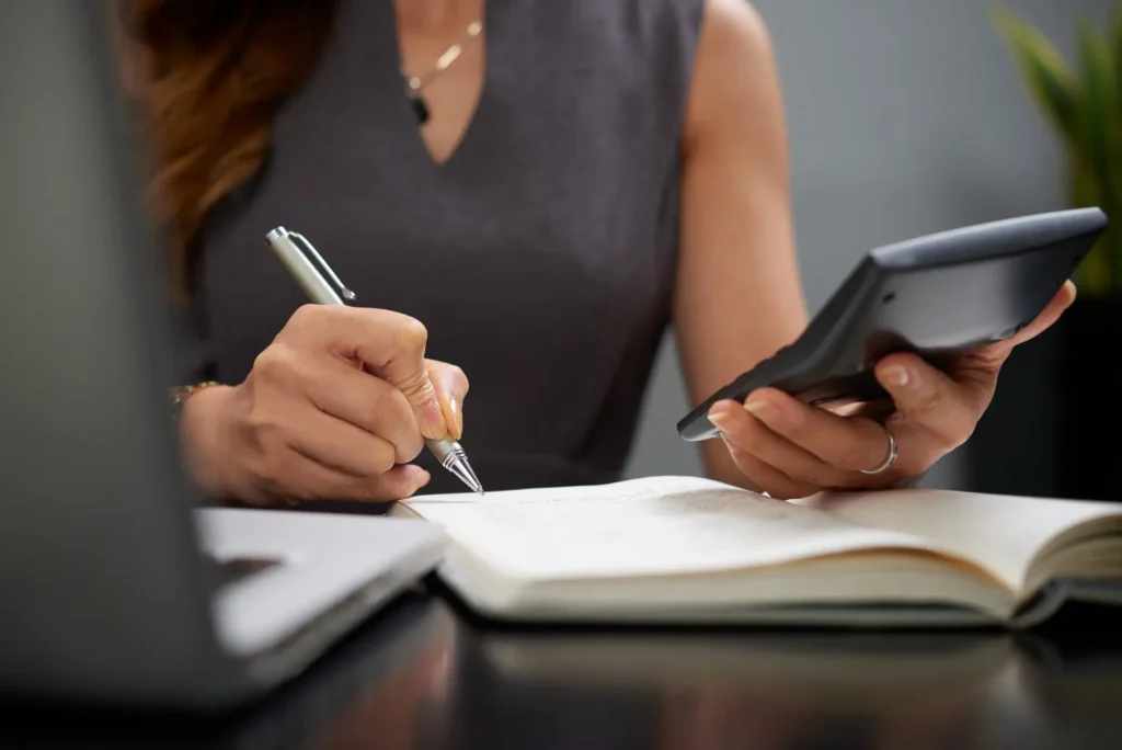 Conselho fiscal de condomínio - Mulher fazendo anotações e utilizando uma calculadora