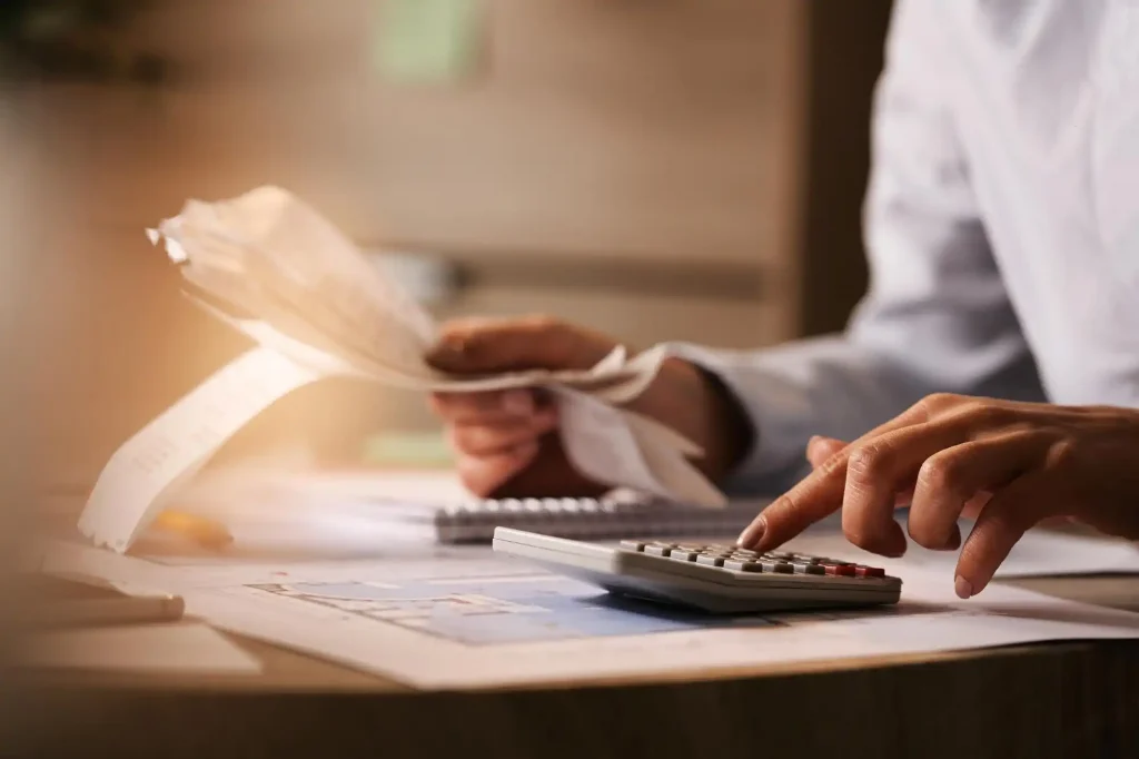 Conselho fiscal de condomínio - Mãos masculinas analisando dados numéricos e utilizando uma calculadora