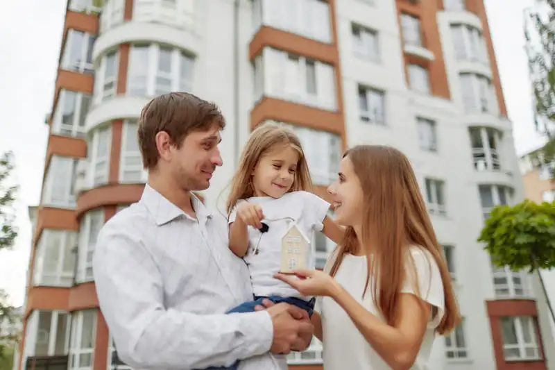 Corretora de Seguros e condomínios: família de mãe, pai e filha juntos com prédio ao fundo