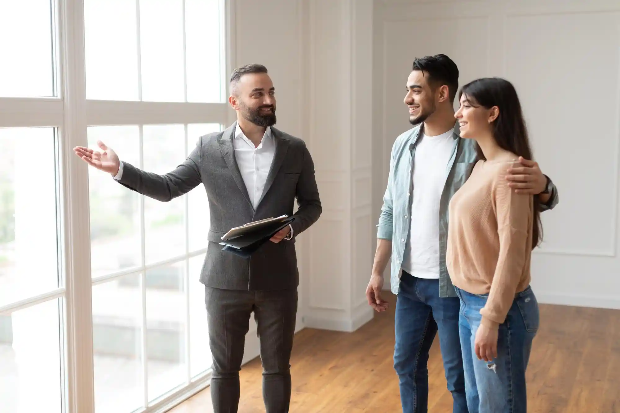 Dicas para corretores de imóveis iniciantes: casal observando a casa apresentada por corretor de imóveis.