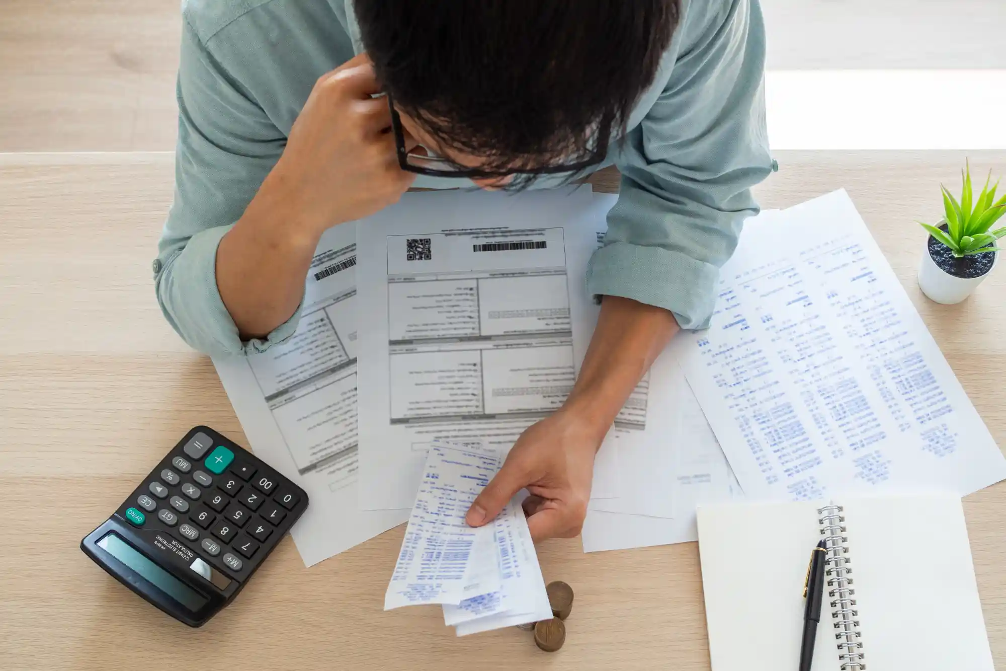 Dívida de condomínio: pessoa vista de cima para baixo com papéis, calculadora e caneta