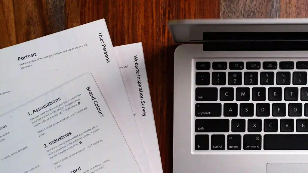 Documentos para alugar imóvel: papéis com documentação em uma mesa de madeira ao lado de um notebook