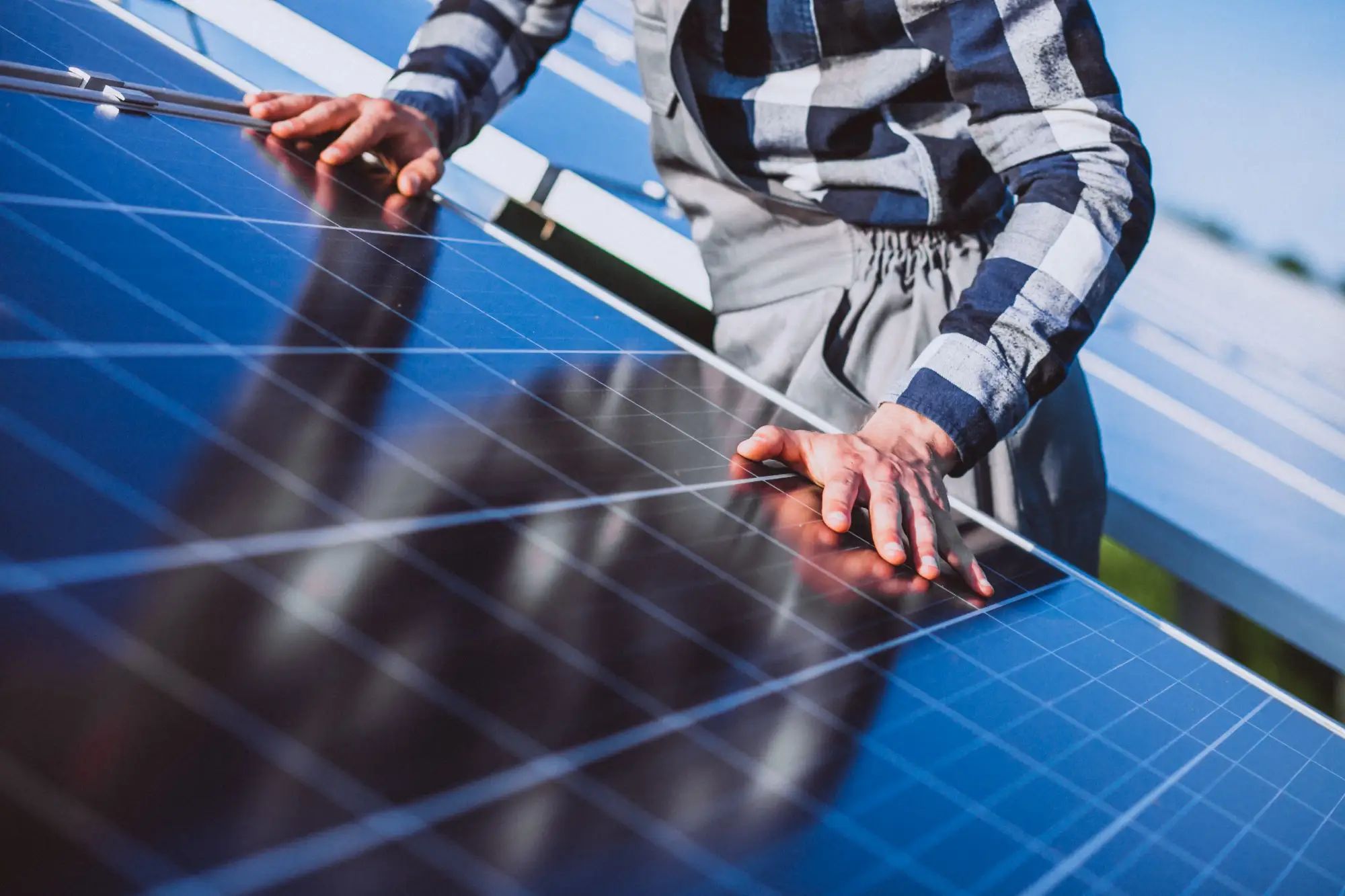 Energia solar em condomínio: homem apoiado em painel solar de cobertura para consertar