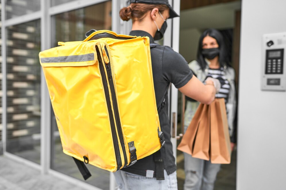 Entrega em condomínio: mulher com mochila nas costas entrega a mercadoria para outra na porta