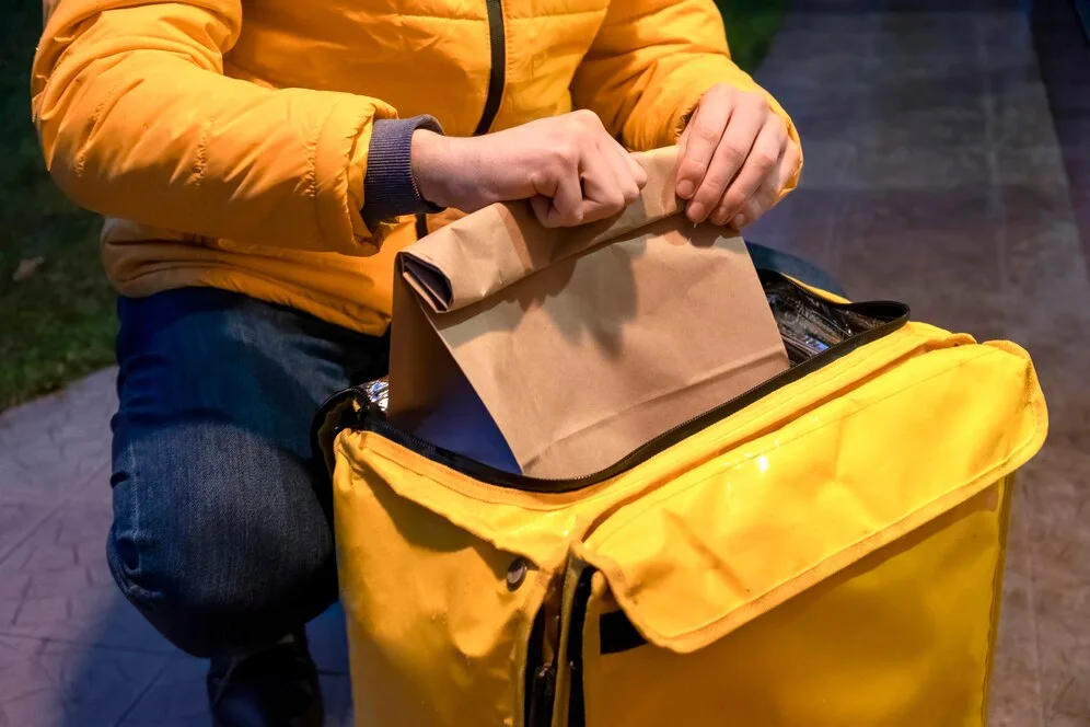 Entrega em condomínio: homem abrindo mochila com delivery para entrega