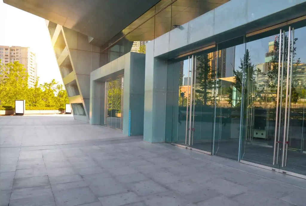 Fachada de condomínio: imagem de uma entrada de condomínio cinza com sol da tarde na lateral.