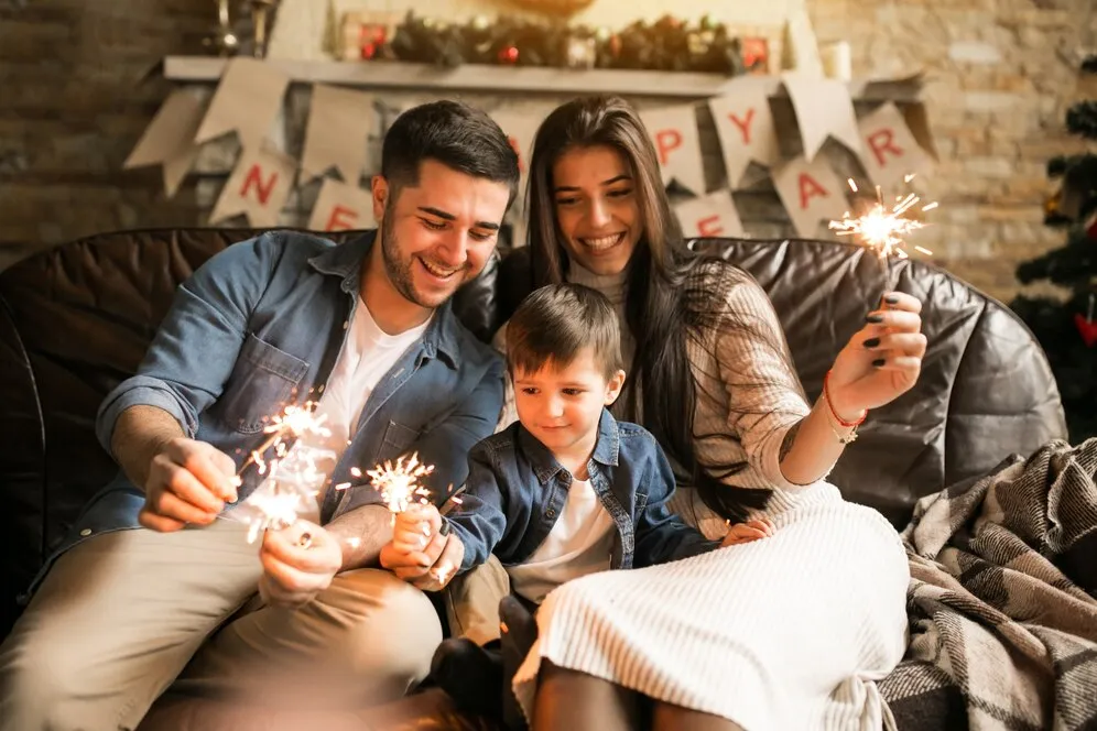 Festa de ano novo em casa: família comemorando o ano novo no sofá
