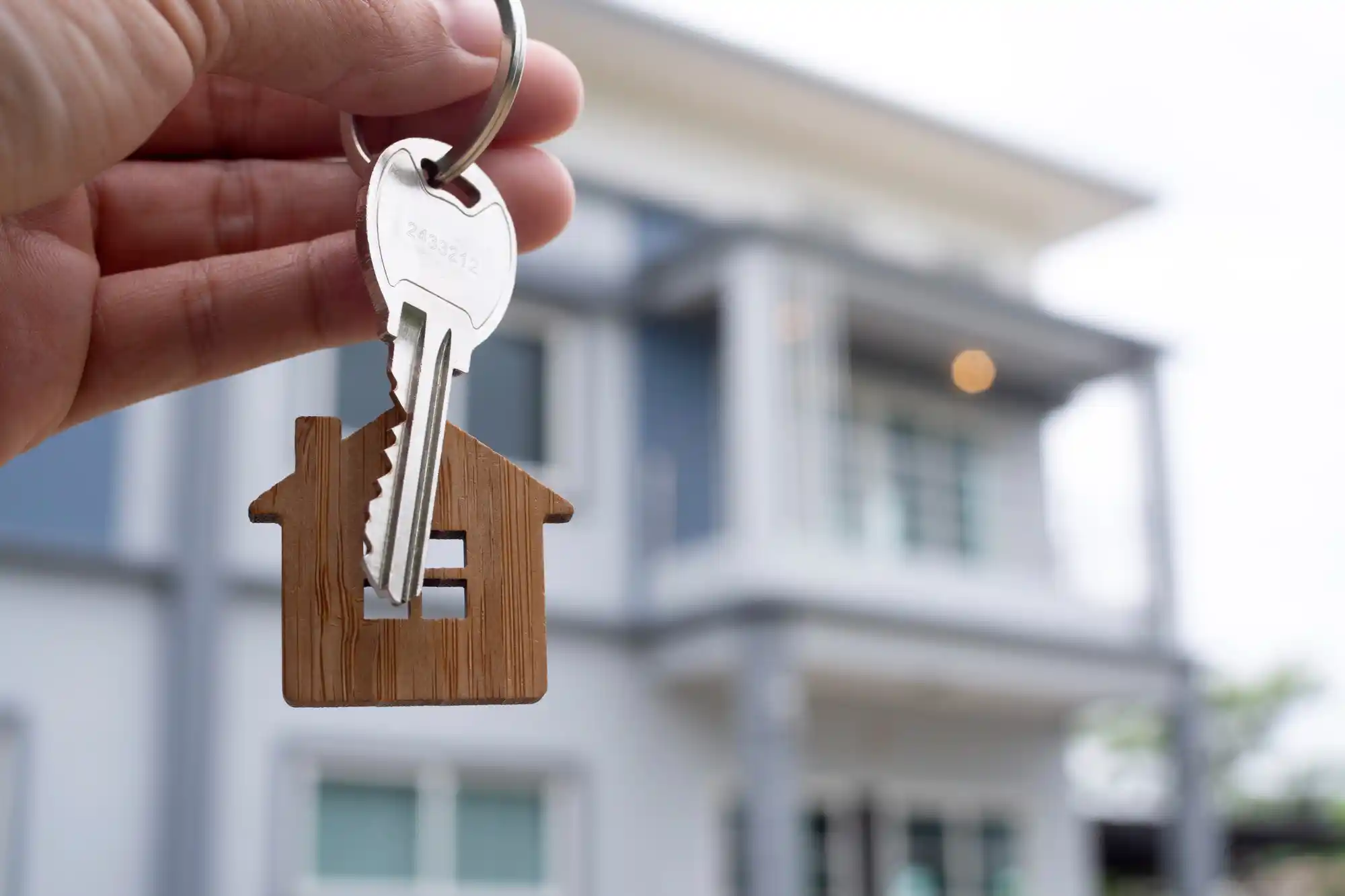 Financiamento imobiliário - como solicitar para comprar sua casa: pessoa segurando chave com sua nova casa de fundo