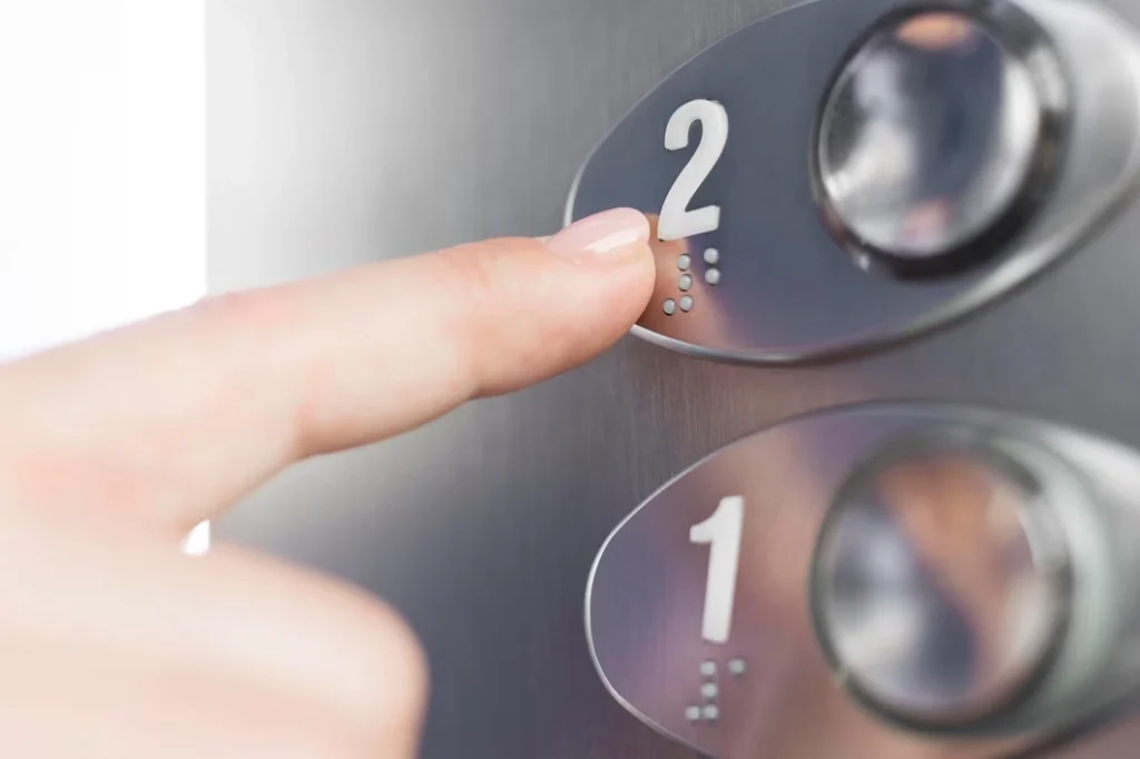 Manutenção de elevador para condomínios: dedo apertando o botão do segundo andar