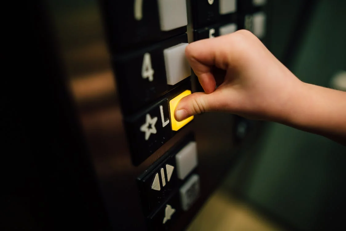 Manutenção de elevador para condomínios: pessoa apertando botão amarelo do elevador