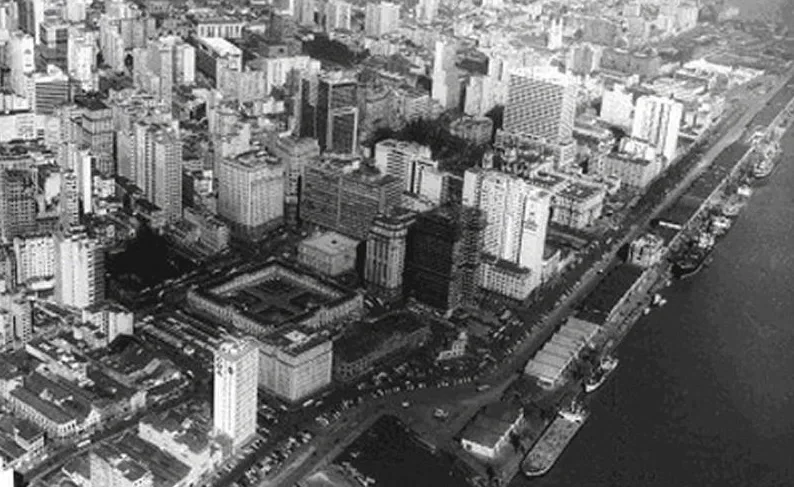Foto aérea em preto e branco do Centro Histórico de Porto Alegre no século XX, com o litoral e diversos prédios.