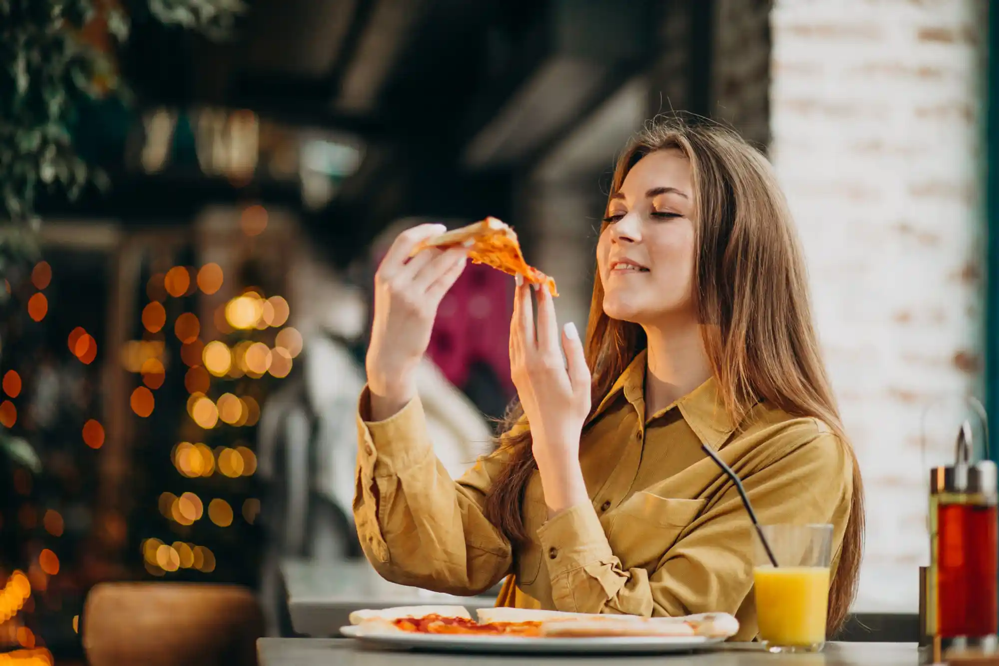 Pizzarias em Porto Alegre: imagem de mulher com roupas amarelas segurando um pedaço de pizza na mão e sorrindo