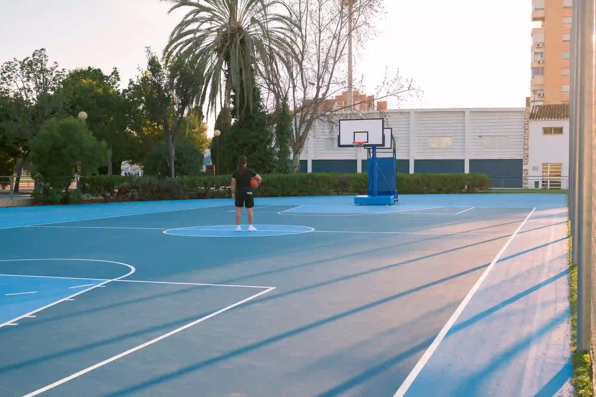 Imagem de pessoa em uma Quadra Poliesportiva, com campo de futsal e cesta de basquete.